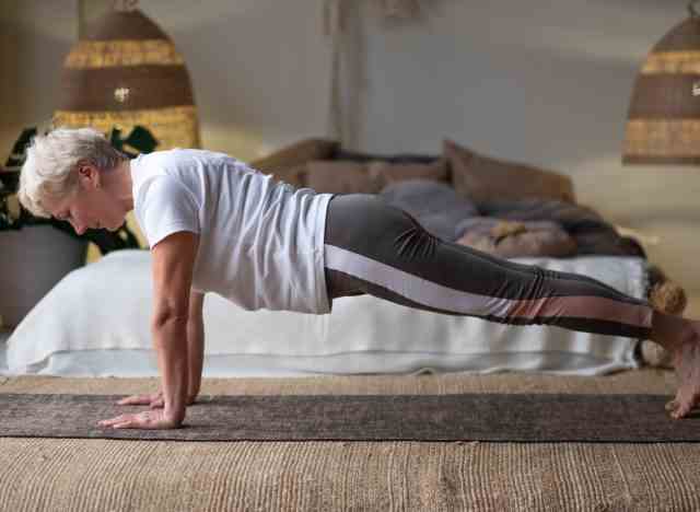 Reife Seniorin, die Plank im Schlafzimmer macht, Teil des Trainings, um 10 Pfund schnell zu verlieren