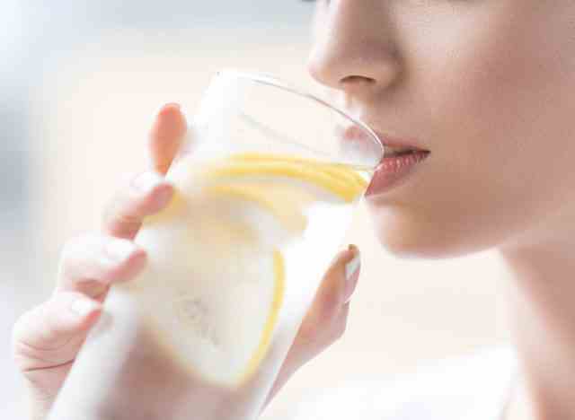 Frau trinkt Zitronenwasser, um hydratisiert zu werden