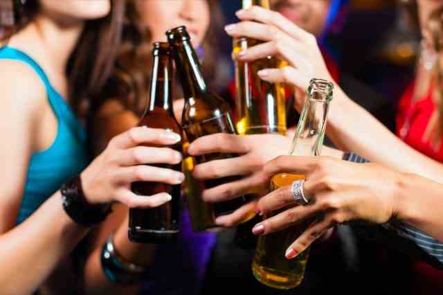 Gruppe von Partymenschen - Männer und Frauen - trinken Bier in einer Kneipe oder Bar