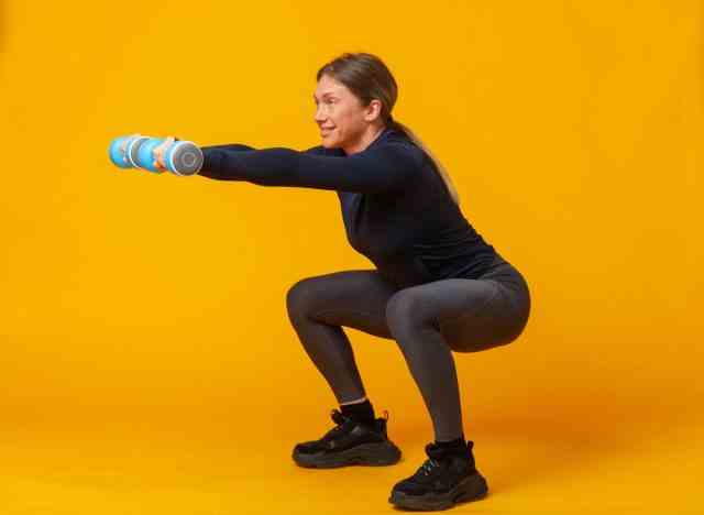 Frau mittleren Alters, die Hantelkniebeugen macht und Übungen zeigt, um Ihre Körperform nach 40 zu verändern