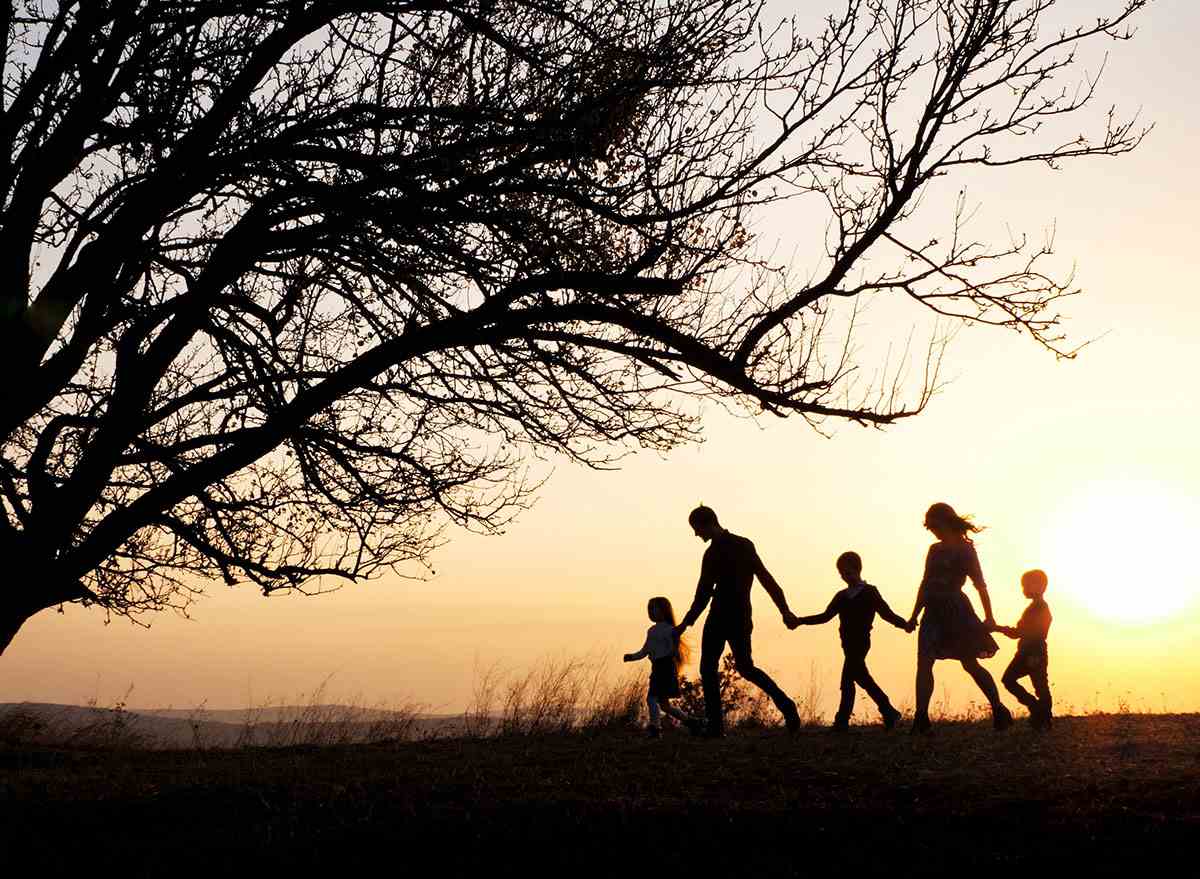 familie mit kindern, die bei sonnenuntergang spazieren gehen