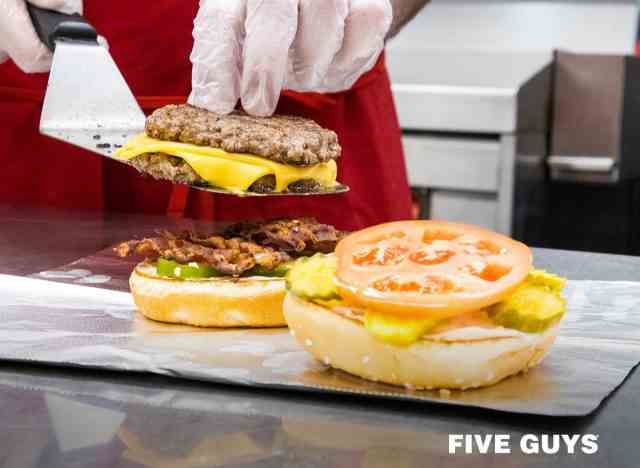 Fünf Mitarbeiter bereiten Burger zu