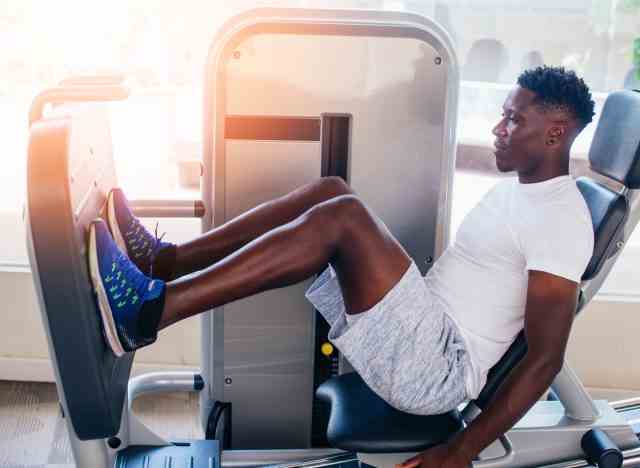 Mann, der eine Beinpresse im Fitnessstudio verwendet und ein Beintraining durchführt, um Muskeln aufzubauen
