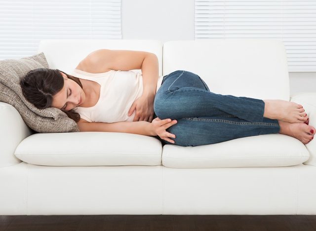 Frau hält Bauch auf Couch