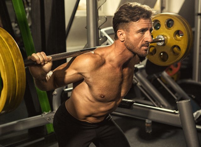 muskulöser Mann im Fitnessstudio macht Langhantel-Kniebeugen, Konzept von Übungen für Männer, um sich aufzublähen