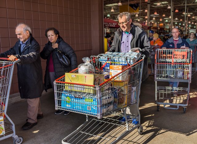 Menschen mit Einkaufswagen voller Lebensmittel gehen aus dem Costco-Laden