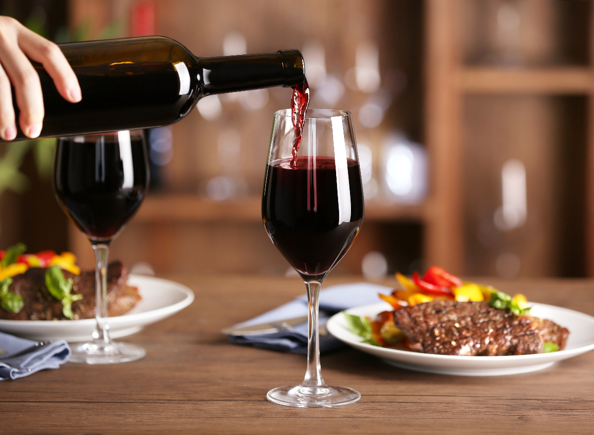 Rotwein in ein Glas neben dem Steak gießen