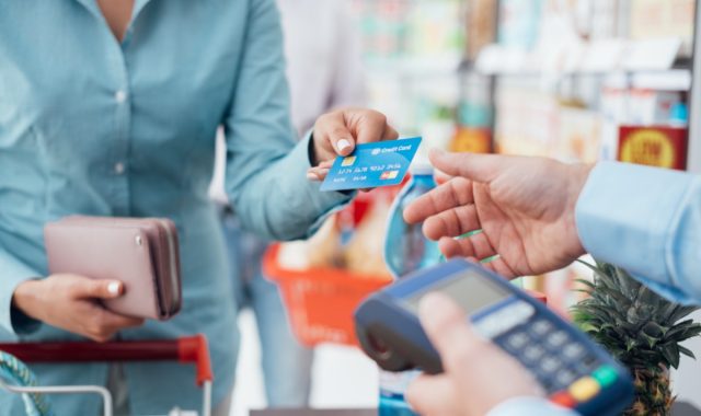 Frau an der Supermarktkasse, sie bezahlt mit Kreditkarte