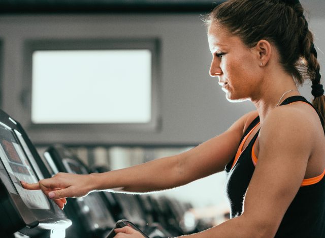 Frau im Fitnessstudio erhöht die Steigung des Laufbandes
