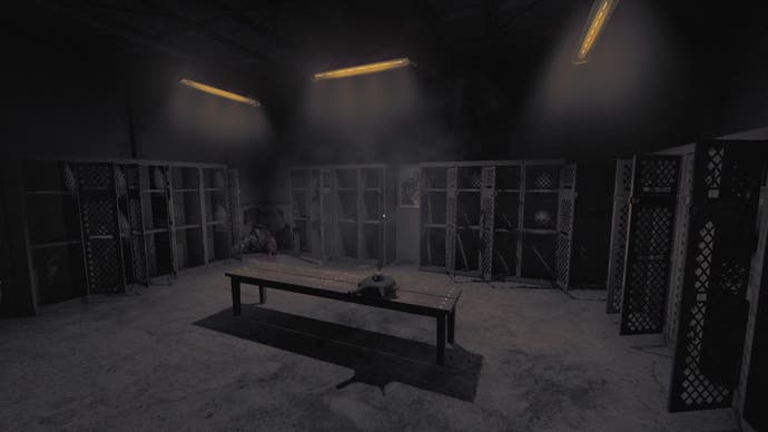 Amnesia: The Bunker Rezensions-Screenshot, der einen Umkleideraum zeigt, in dem die meisten Schließfächer offen stehen.  Eine Leiche wird in einer Ecke des Raumes abgelegt, aber im gedämpften Licht kann man sie nur von der Truhe abwärts sehen.