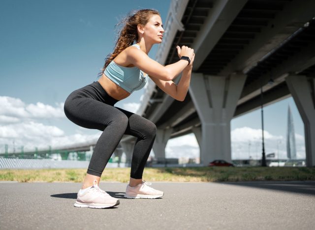 Frau macht Kniebeugenübungen im Freien, Trainingskonzept, um hängendes Bauchfett zu schrumpfen