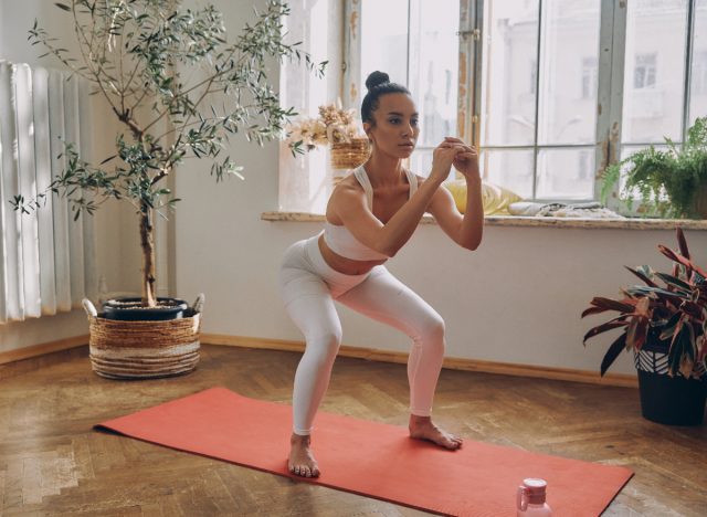 Frau macht Kniebeugen im Körpergewicht auf einer Yogamatte