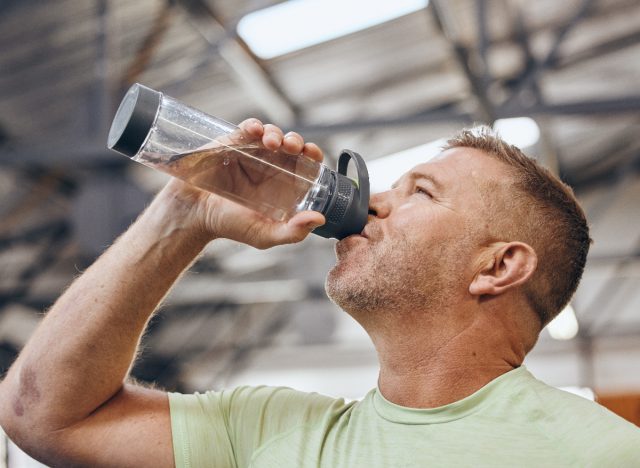 Reifer Mann trinkt Wasserflasche während des Trainings