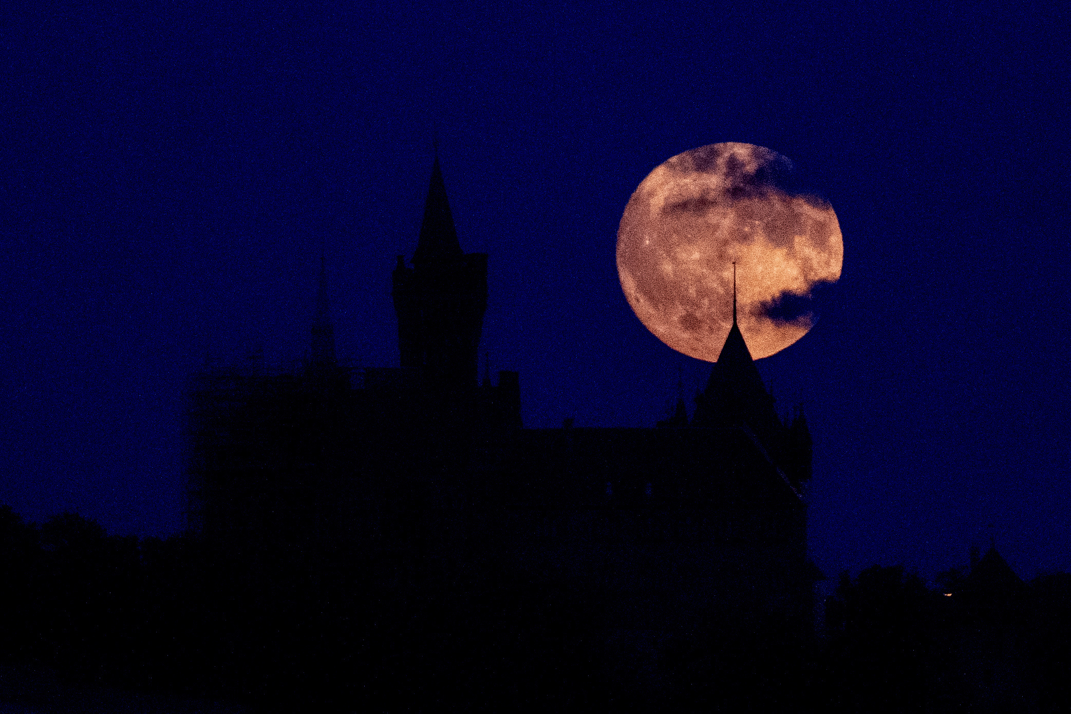 Der atemberaubende Mond geht hinter dem Schloss Wernigerode in der Nähe des Harzes in Deutschland auf