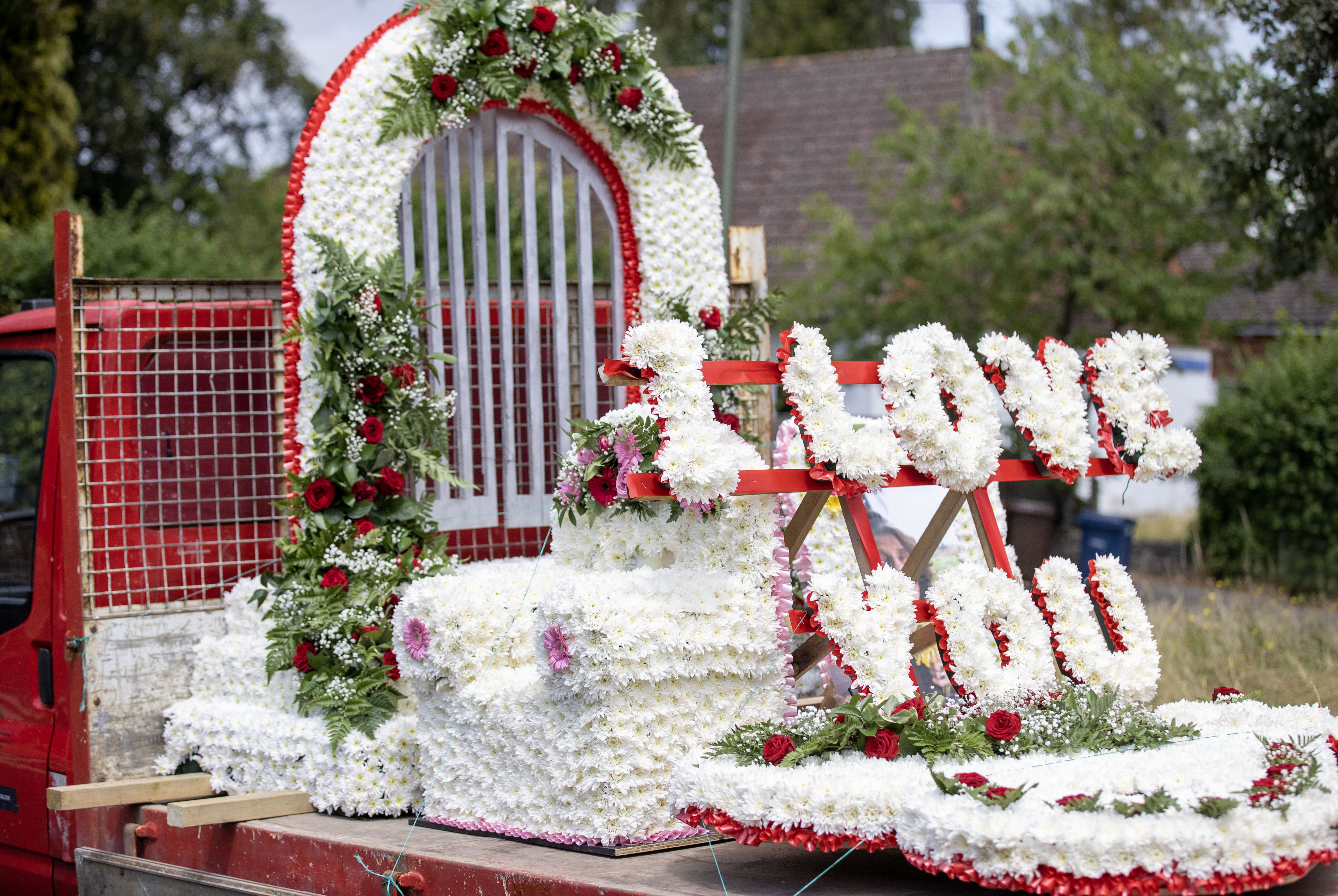 Eine florale Hommage mit der Aufschrift „Ich liebe dich“ auf einem Tieflader bei der Beerdigung