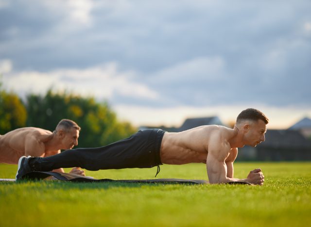 Reifer, muskulöser Mann beim Planken im Freien im Gruppenfitnesskurs