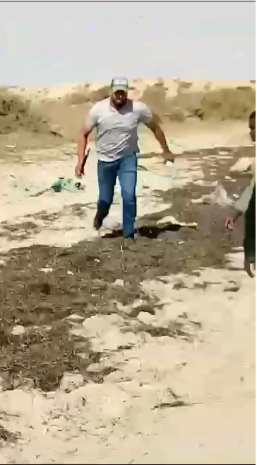 Dies ist ein Screenshot eines Videos, das einen tunesischen Mann in Zivil zeigt, der mit einem Schlagstock bewaffnet versucht, eine dort gefangene Gruppe von Migranten anzugreifen.