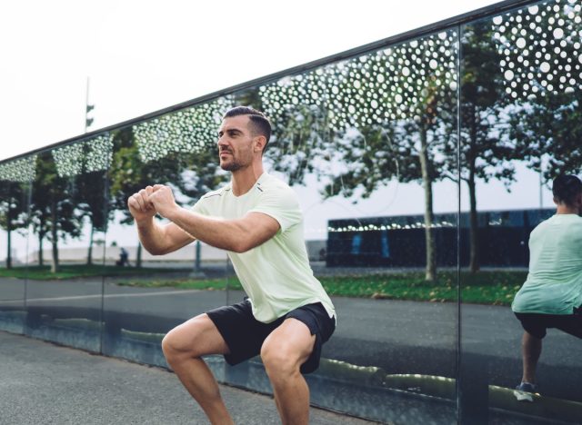 Muskulöser Mann macht Kniebeugen mit Körpergewicht, Übungen für Männer zum Muskelaufbau