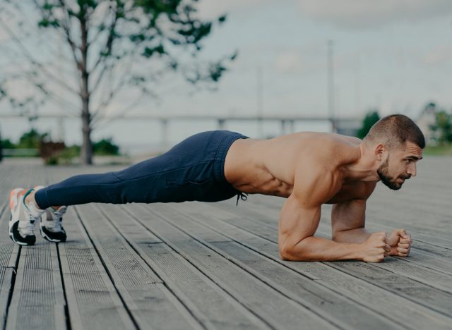 Muskulöser Mann beim Unterarmplanken im Freien, Konzept täglicher Übungen für Männer, um definierte Bauchmuskeln zu bekommen