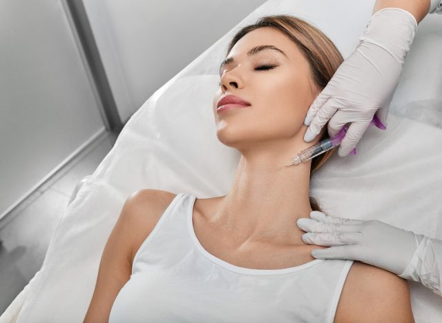 Frau bekommt Botox-Injektion in den Hals