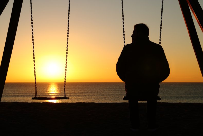 Mann sitzt allein auf der Schaukel bei Sonnenuntergang
