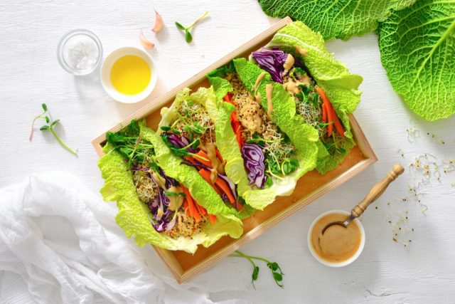 Vegane Detox-Frühlingsrollen mit Quinoa, Sprossen und thailändischer Erdnusssauce, Blick von oben, flach liegend
