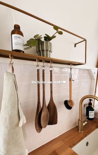 Im Küchenbereich hängen an den Wänden Utensilien und ein goldener Wasserhahn