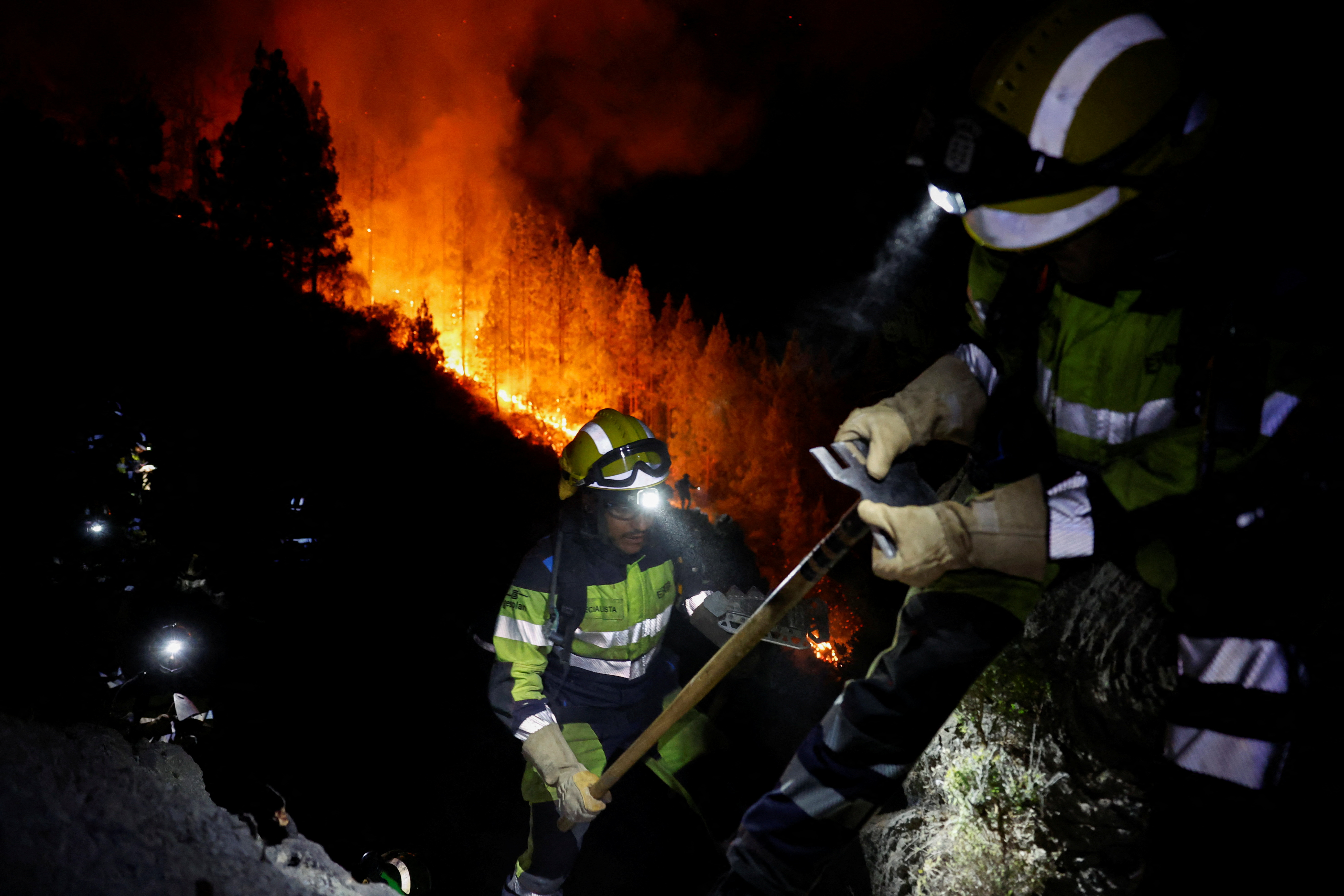 Feuerwehrleute bekämpfen die Flammen in einem Wald in Arafo