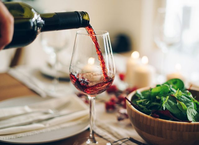 Gießen Sie ein Glas Rotwein mit Alkohol zum Abendessen