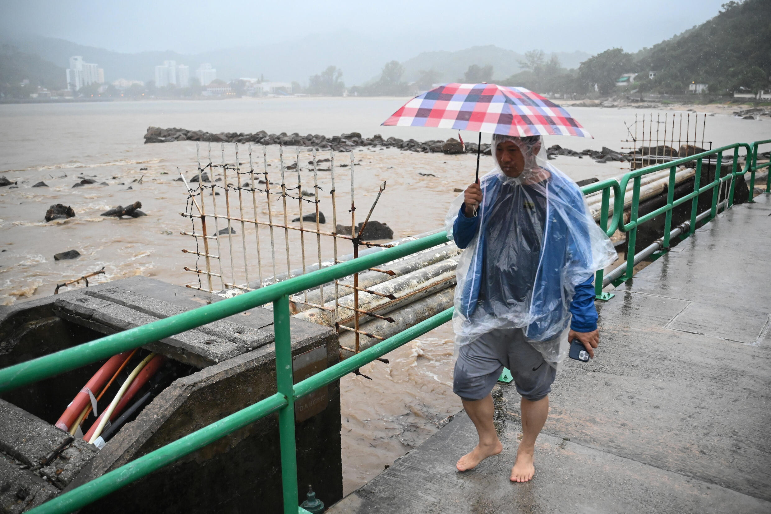 Ein Mann geht auf einer Brücke über einen anschwellenden Fluss auf der Insel Lantau in Hongkong.