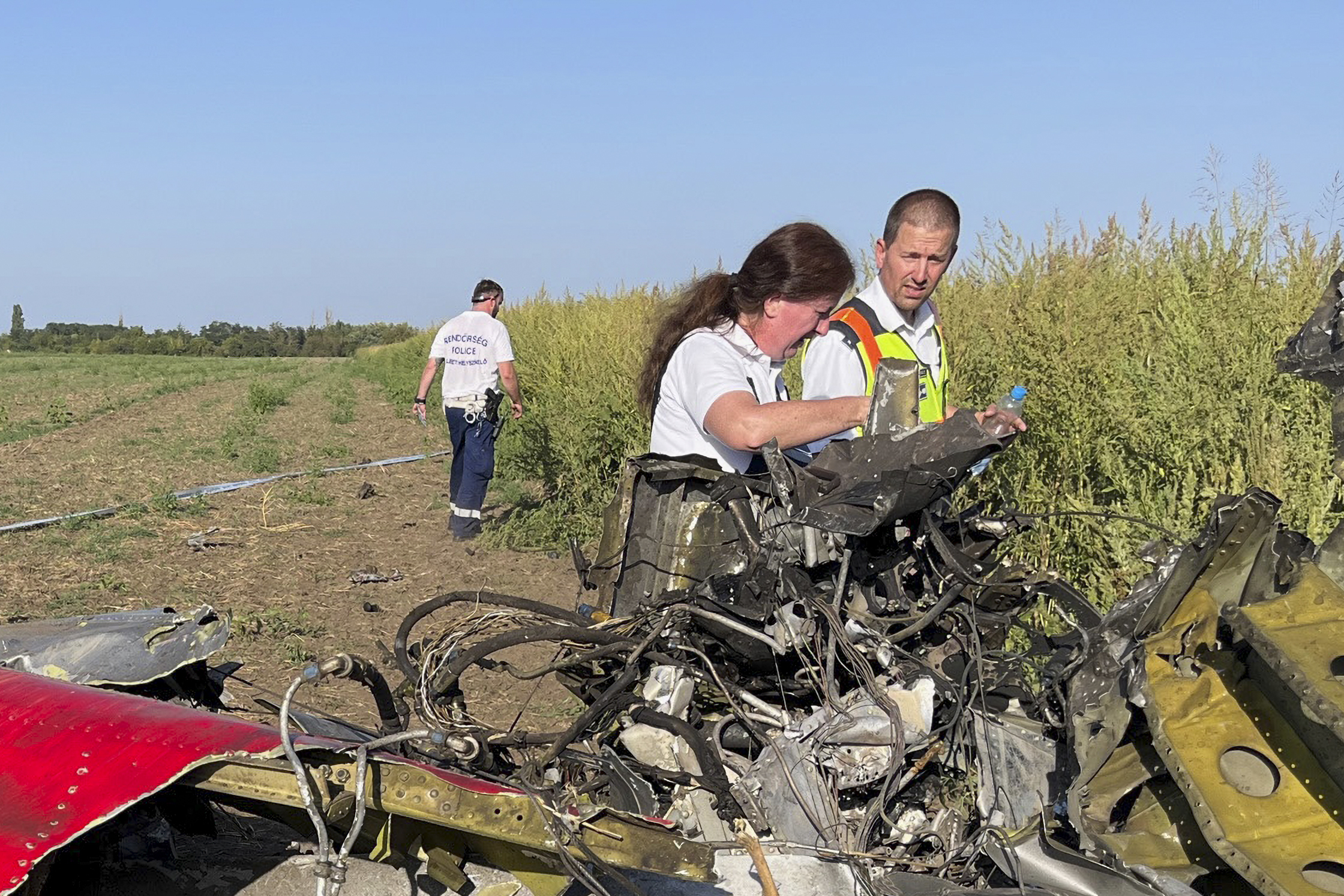 Polizisten untersuchen die Trümmer des Flugzeugabsturzes, bei dem zwei Menschen getötet und drei verletzt wurden