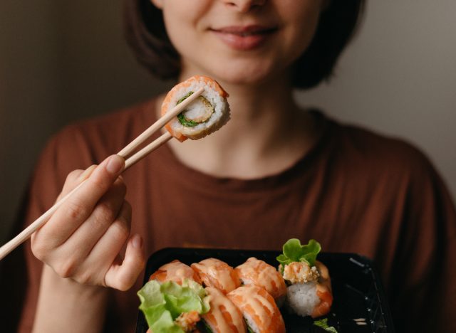 Nahaufnahme einer Frau, die Sushi isst, Konzept überraschender Gewohnheiten, die zu einer schnellen Gewichtszunahme führen