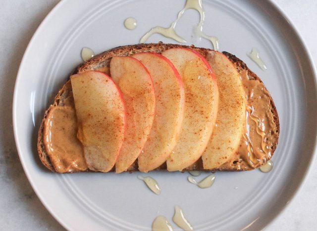 Apfel-Erdnussbutter-Zimt-Honig-Toast auf grauem Teller und Marmortheke