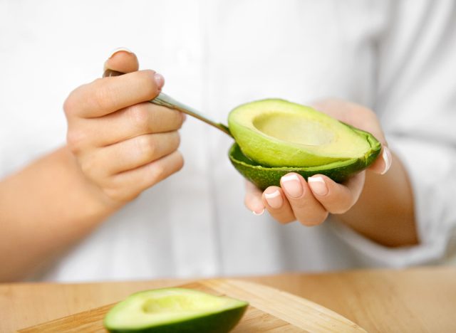 Nahaufnahme beim Auslöffeln einer Avocado, Konzept von Gewohnheiten, die den Gewichtsverlust zerstören