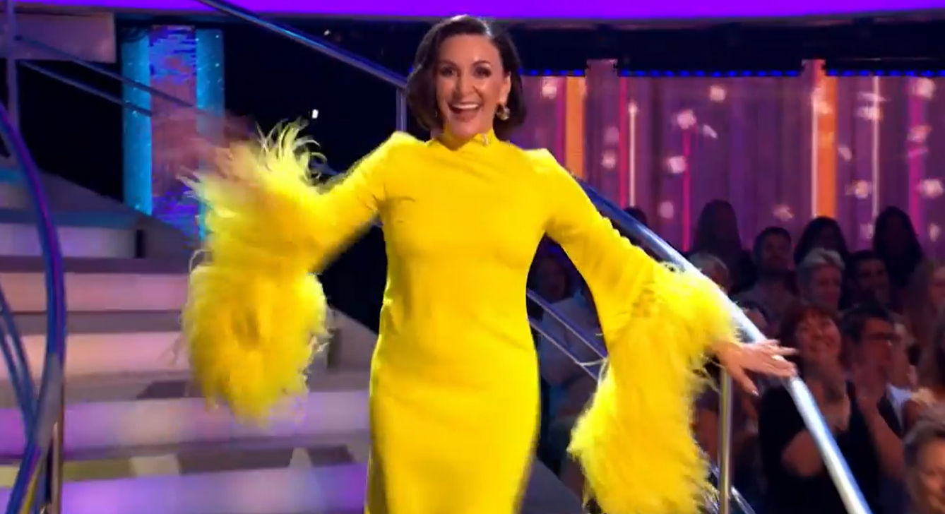 Shirley trug ein leuchtend gelbes Kleid mit dramatischen Federärmeln
