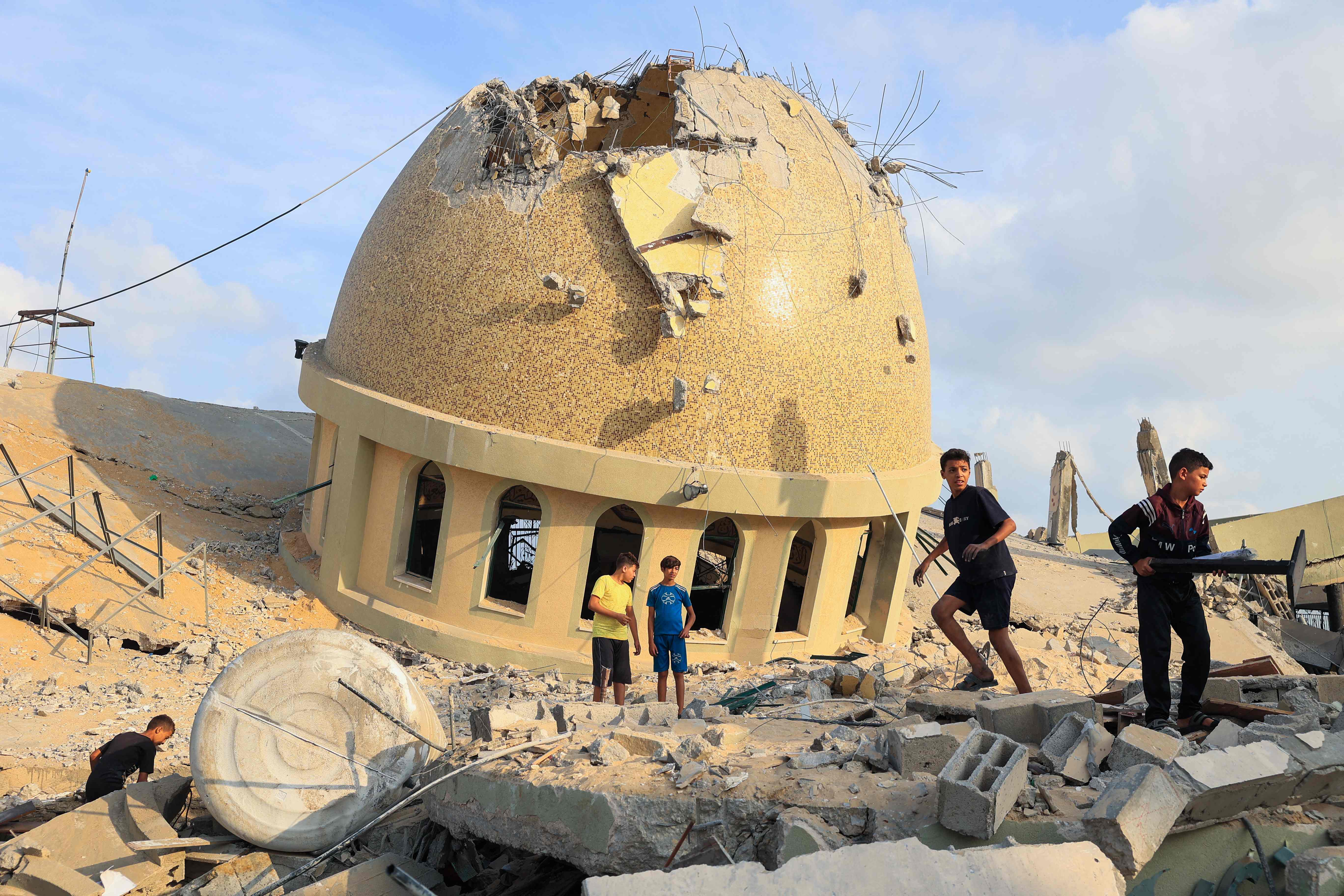 Children are seen walking through the ruins of a bombed-out mosque in the south of the Gaza Strip