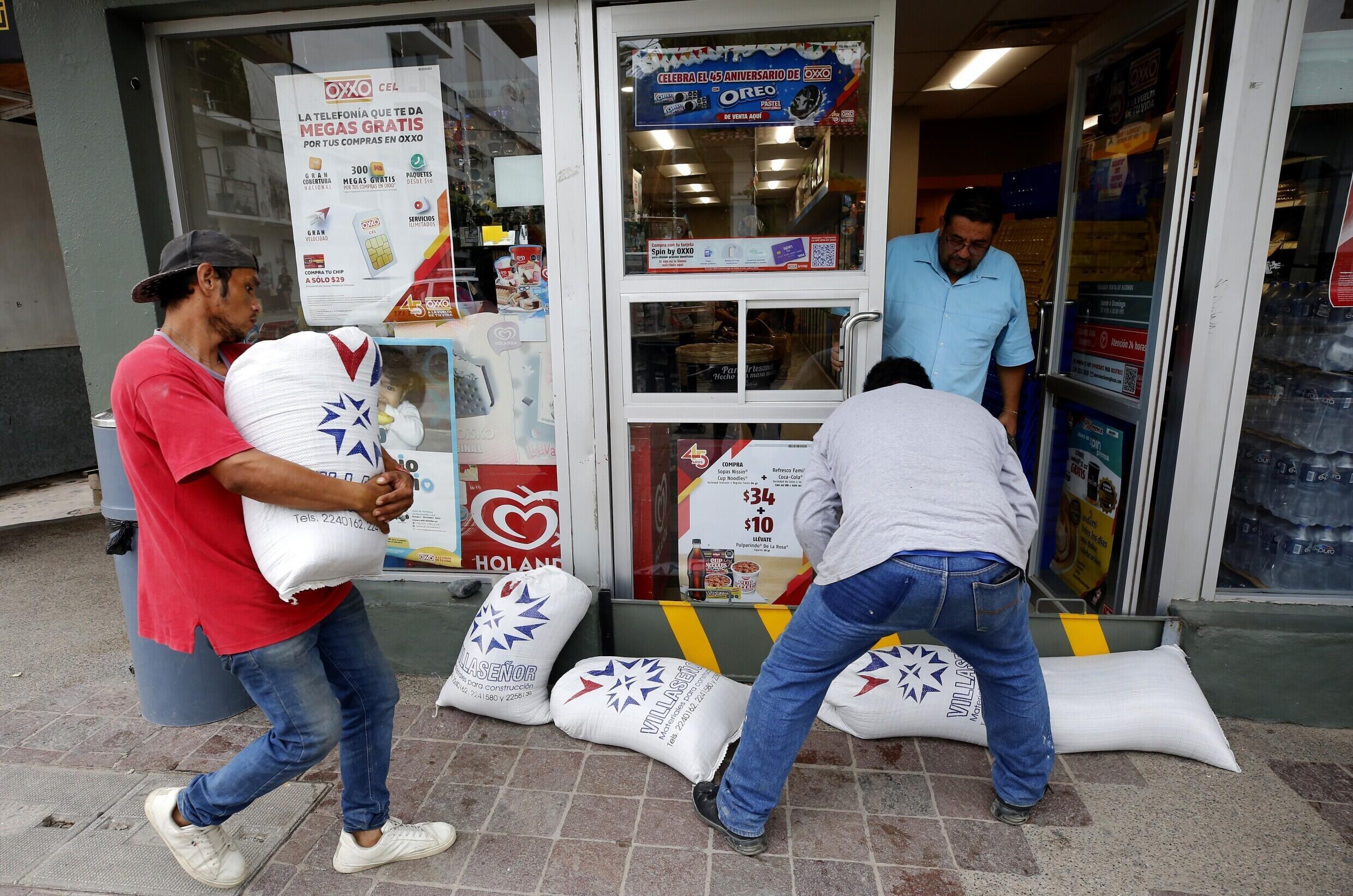 Arbeiter platzieren Sandsäcke vor einem Geschäft im mexikanischen Puerto Vallarta, um sich vor möglichen Überschwemmungen zu schützen