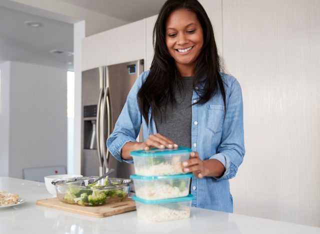 Glückliche Frau, die Reis und Brokkoli in Behältern zubereitet, Konzept der Gewohnheiten, um diese Woche mit dem Abnehmen zu beginnen