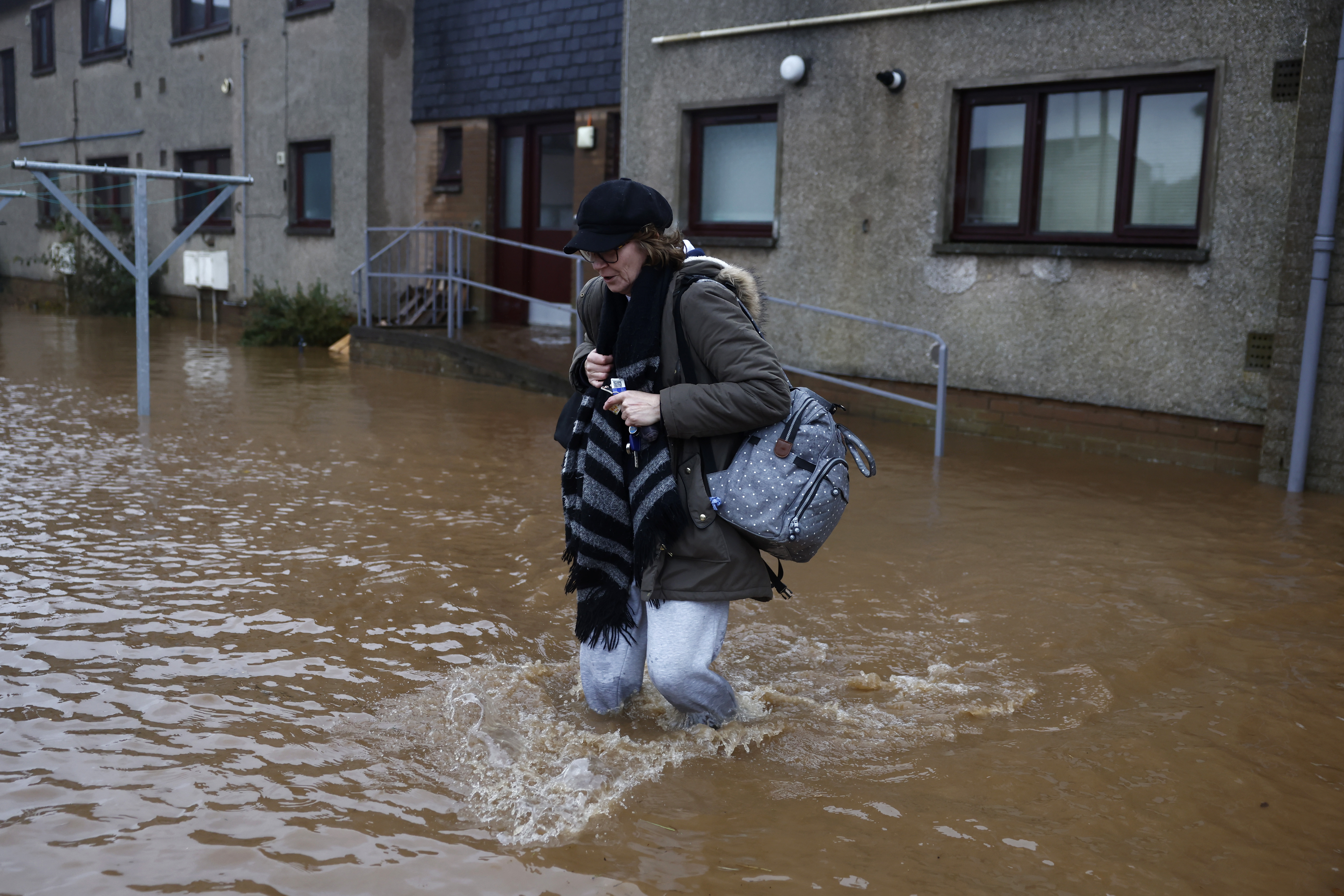 A woman wades through the flood waters near some houses in Brechin