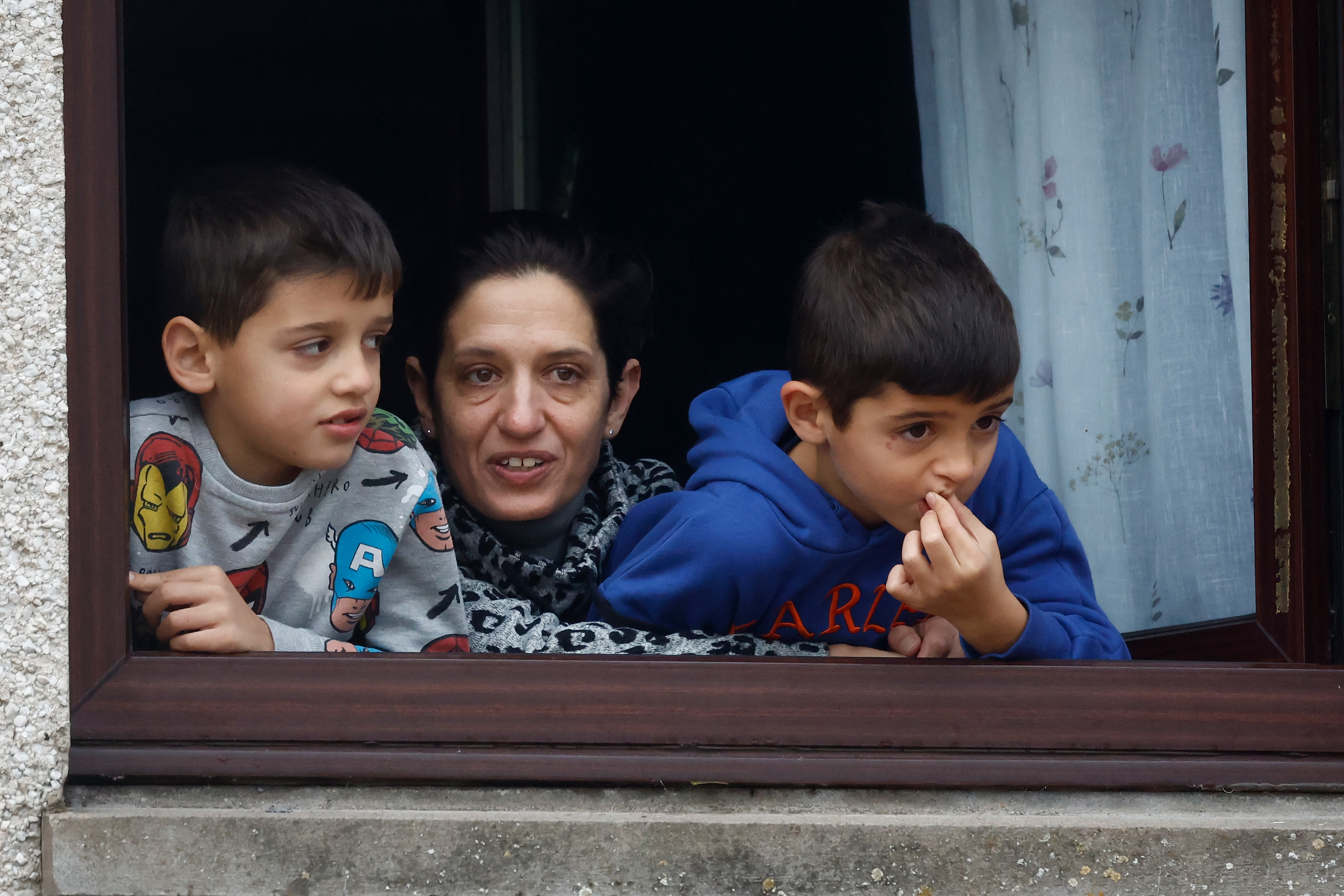 A woman and two boys looked worried as they stared out of a window at the chaos