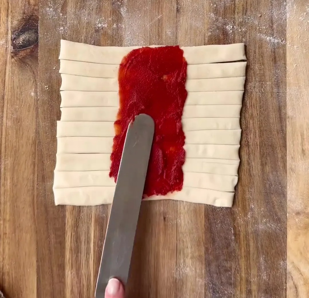Mit einem Messer Tomatensauce auf dem festen Mittelteil verteilen