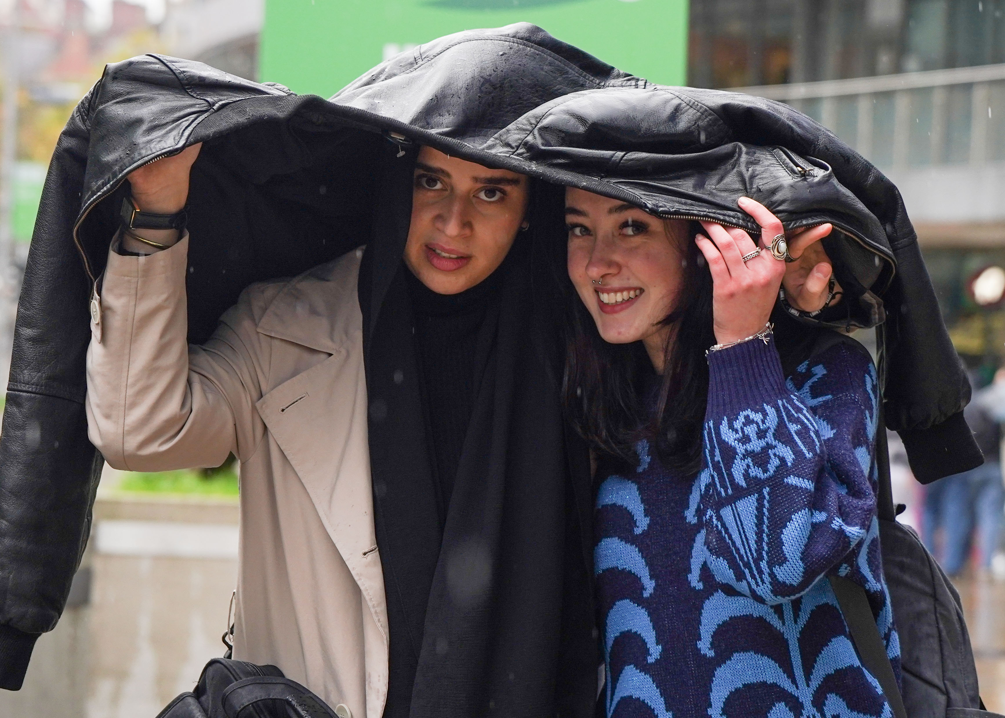 In Manchester schützen sich Käufer unter ihren Mänteln vor dem Regen