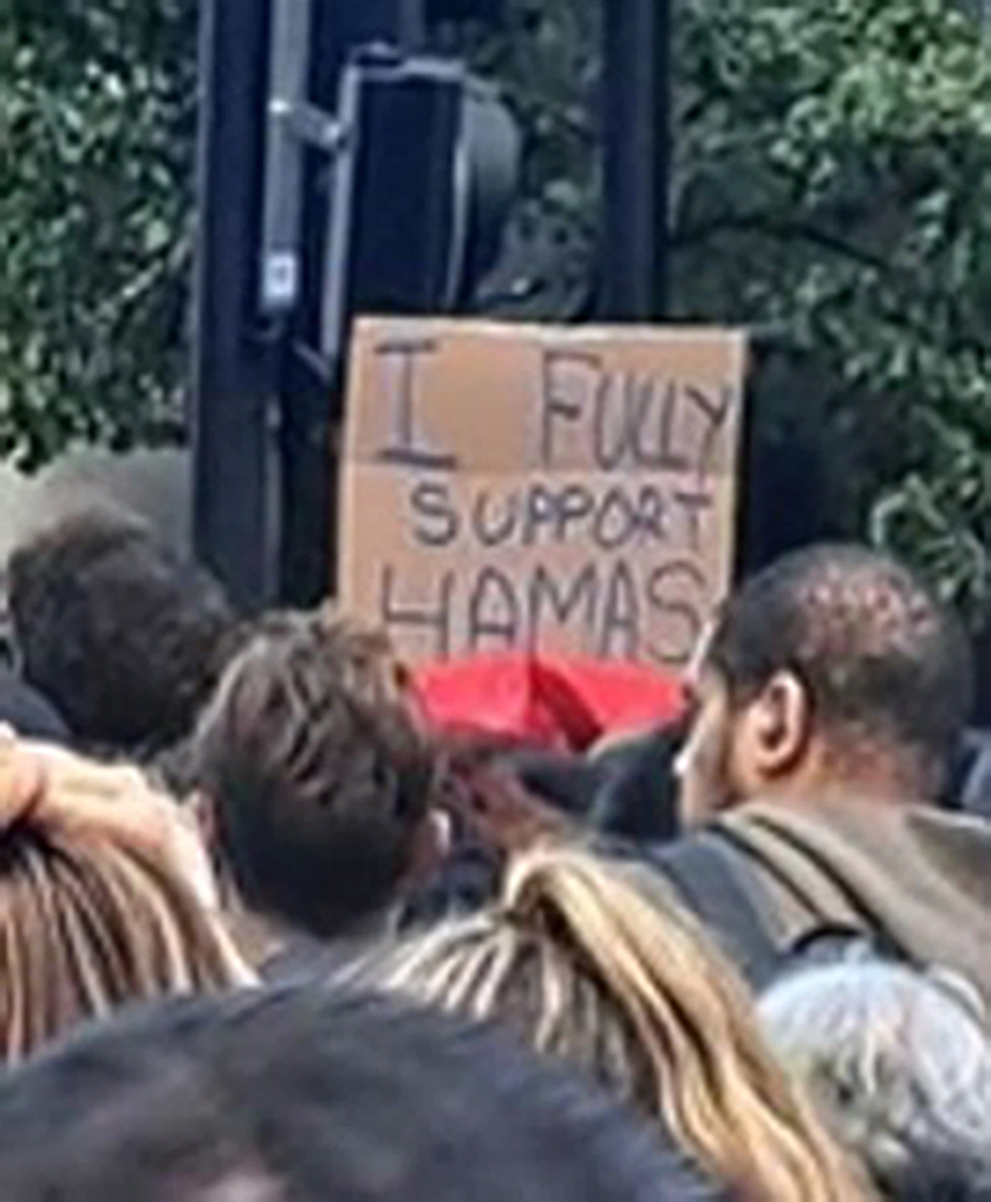 Ein Mann, der ein Plakat mit der Aufschrift „Ich unterstütze die Hamas voll und ganz“ in der Hand hält, wird ebenfalls zur Vernehmung durch die Polizei gesucht