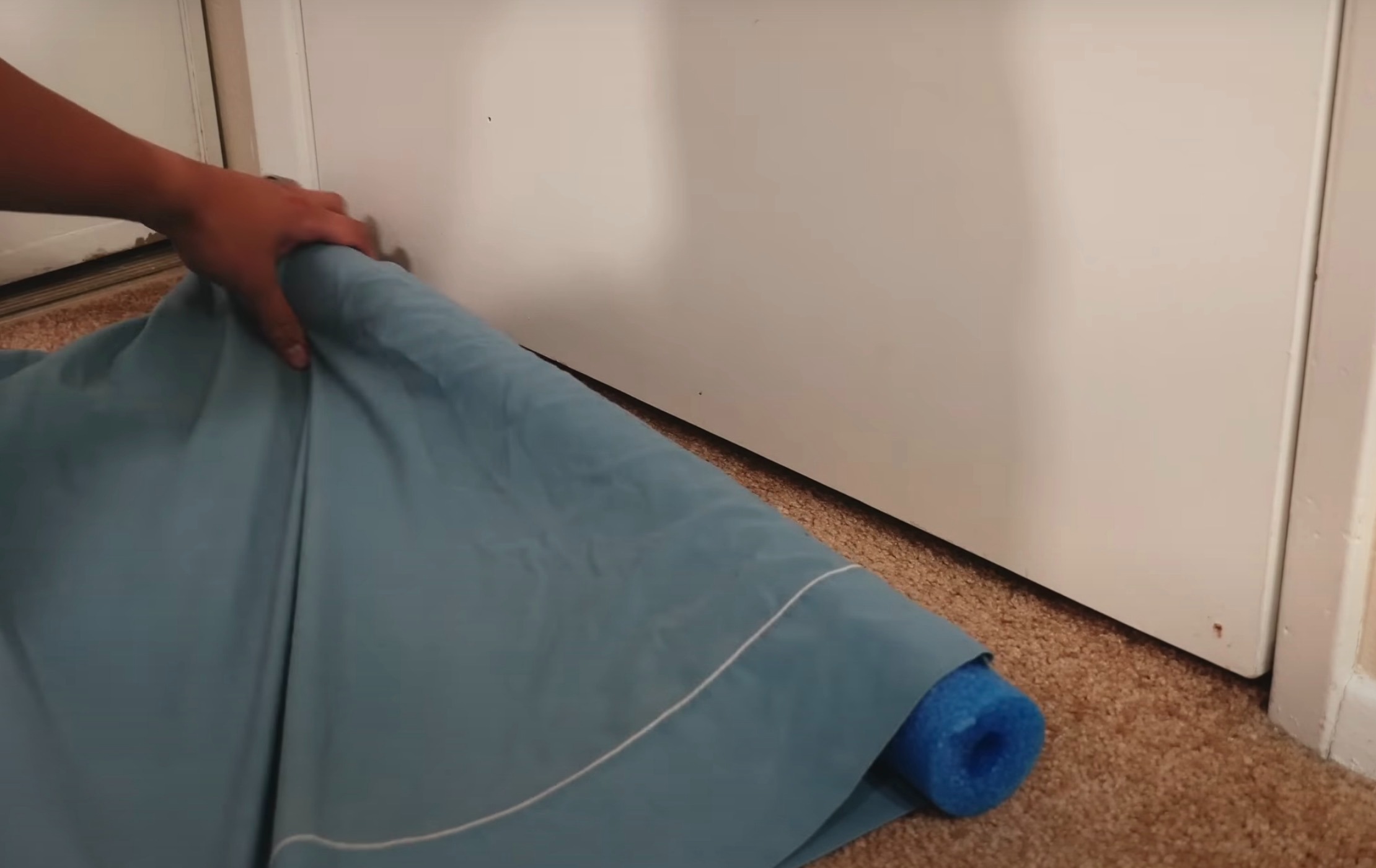 Der YouTuber schnitt die Poolnudel so zu, dass sie neben die Tür passte, bevor er sie in einen alten Kissenbezug wickelte