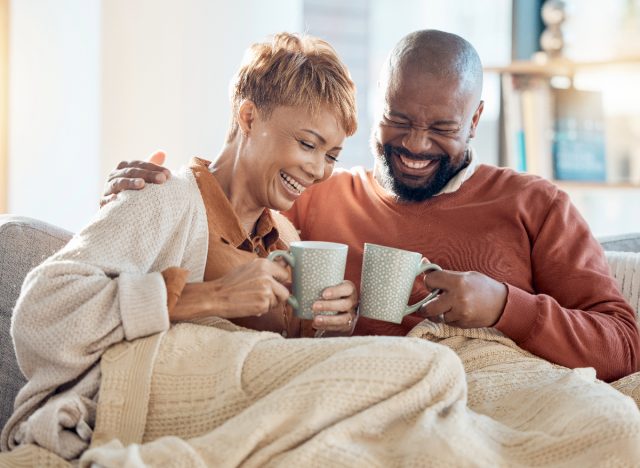 Glückliches Paar, das morgens mit Kaffee auf der Couch kuschelt