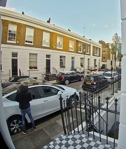 Auf Aufnahmen einer Klingeltür ist zu sehen, wie Diebe am helllichten Tag in eine Straße in Chelsea geparkte Luxusautos spähen