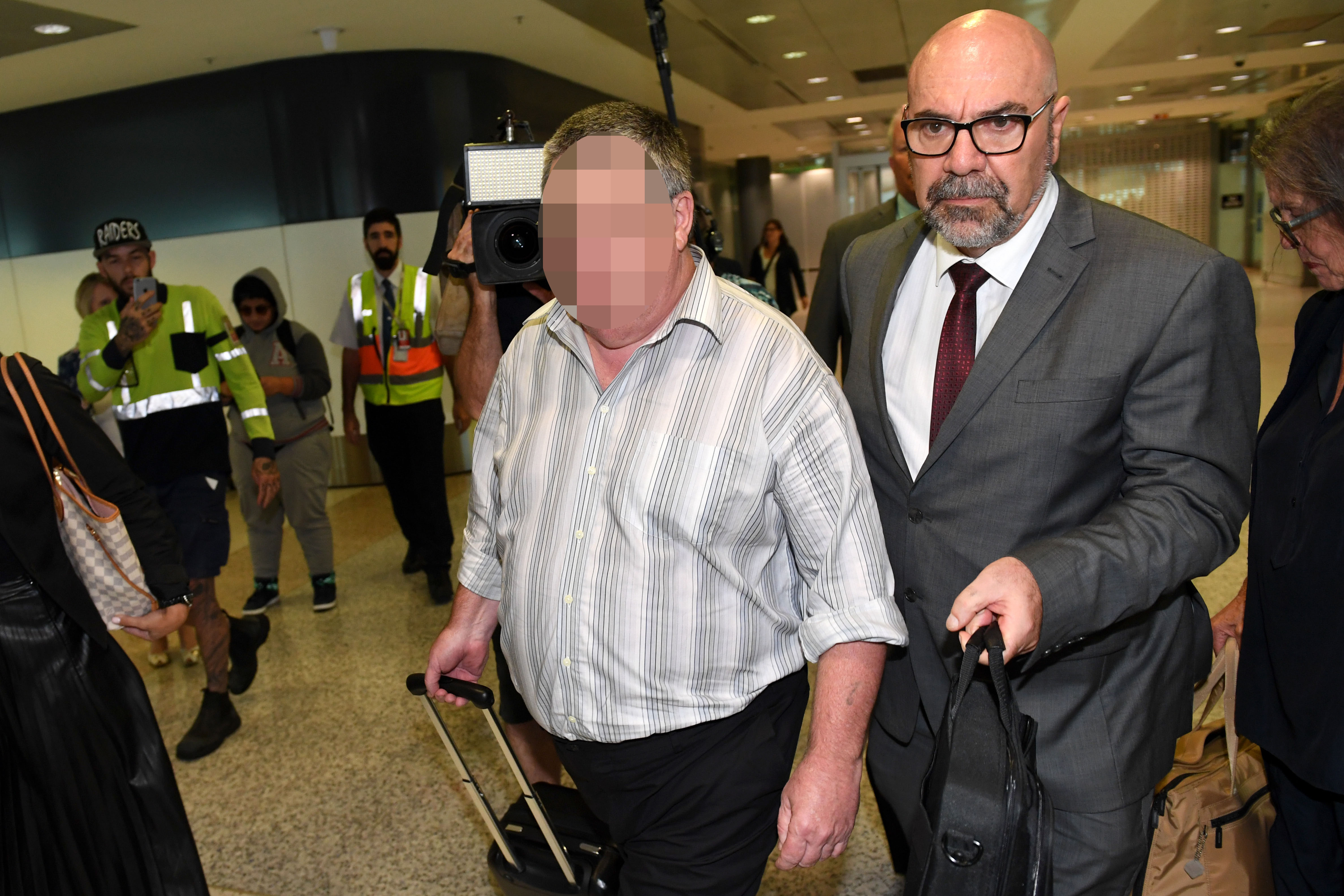 Ein Mann (links), der im Zusammenhang mit der Entführung und Ermordung von Cheryl Grimmer im Jahr 1970 aus Victoria ausgeliefert wurde, wird 2017 von der NSW-Polizei auf einem Flughafen eskortiert