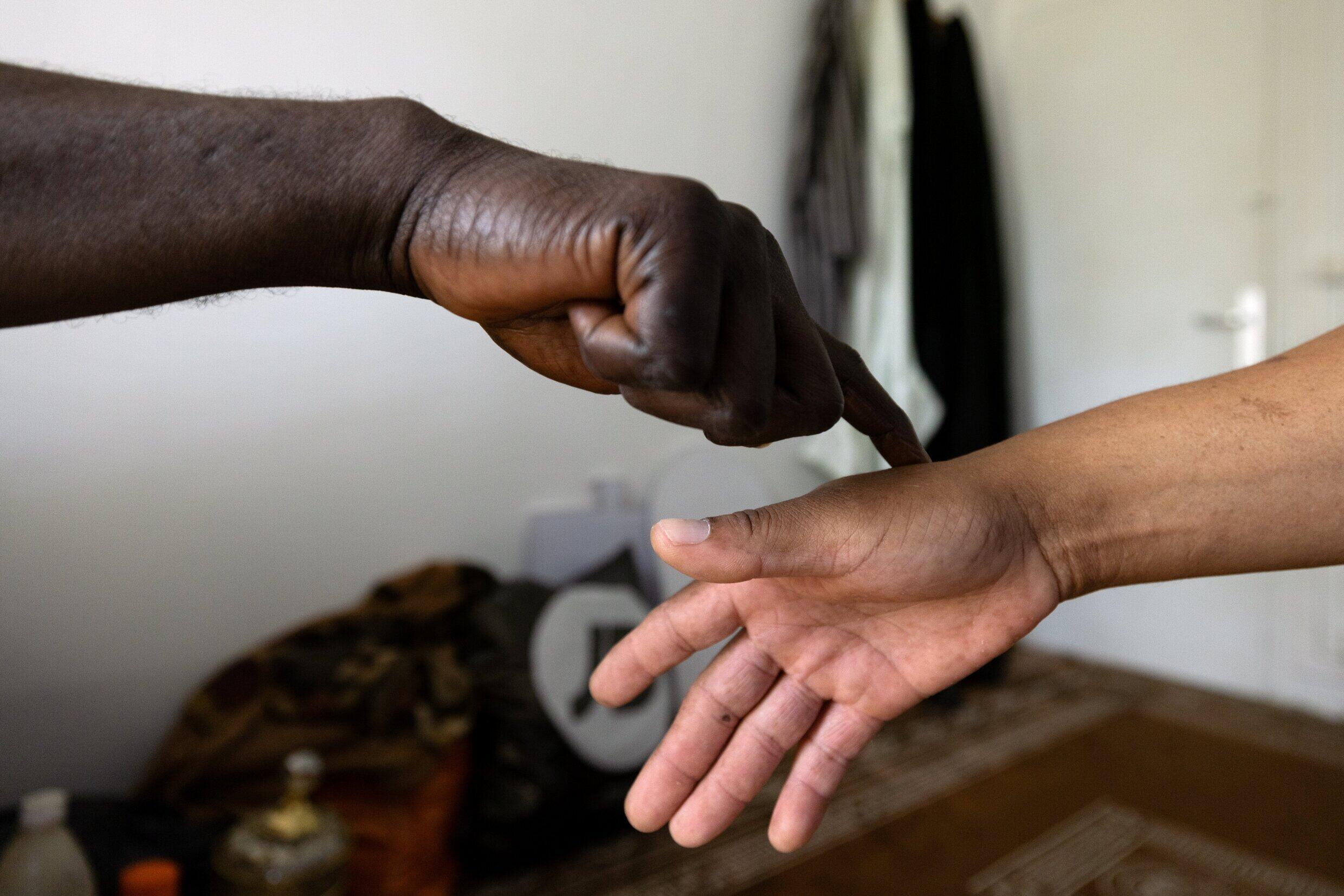 Der afrikanische Wunderheiler Sheikh Issa testet vor einer Beratung die Hand seines Klienten Raymond.