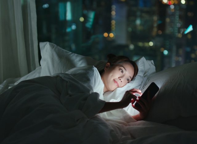Frau scrollt im Bett durch soziale Medien