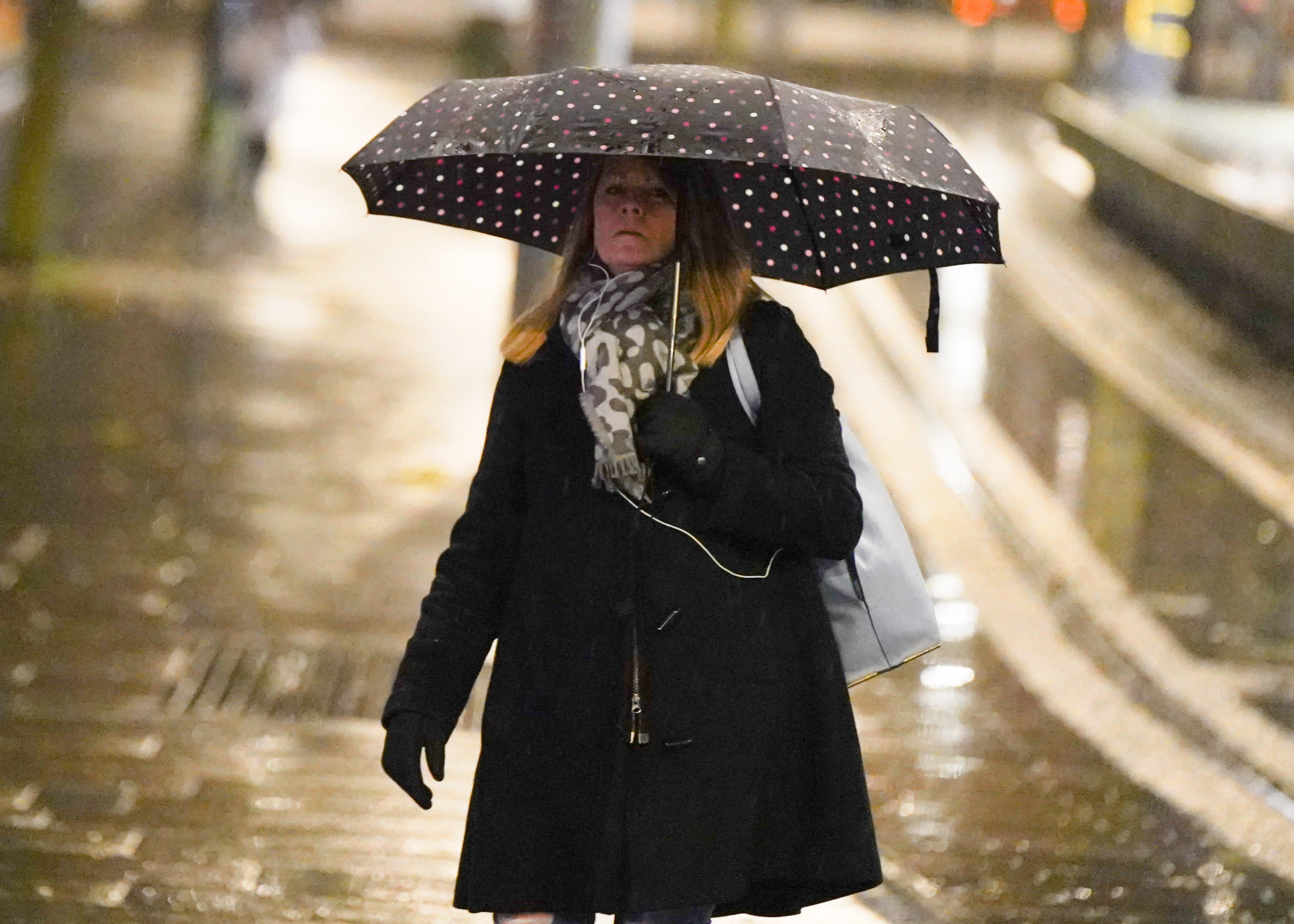 Eine Frau in Manchester schützt sich mit ihrem Regenschirm vor dem Regen